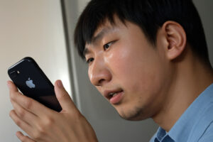 A close-up of a young man with a blank expression scrolling mindlessly through his phone